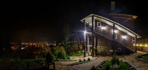 A multi-story building with a staircase, outdoor lighting, and a view of a cityscape at night. - FAVAR Carpathians (Skhidnytsia)