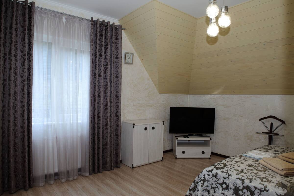 Quarto com cama, televisão, guarda-roupa e luminária no teto.