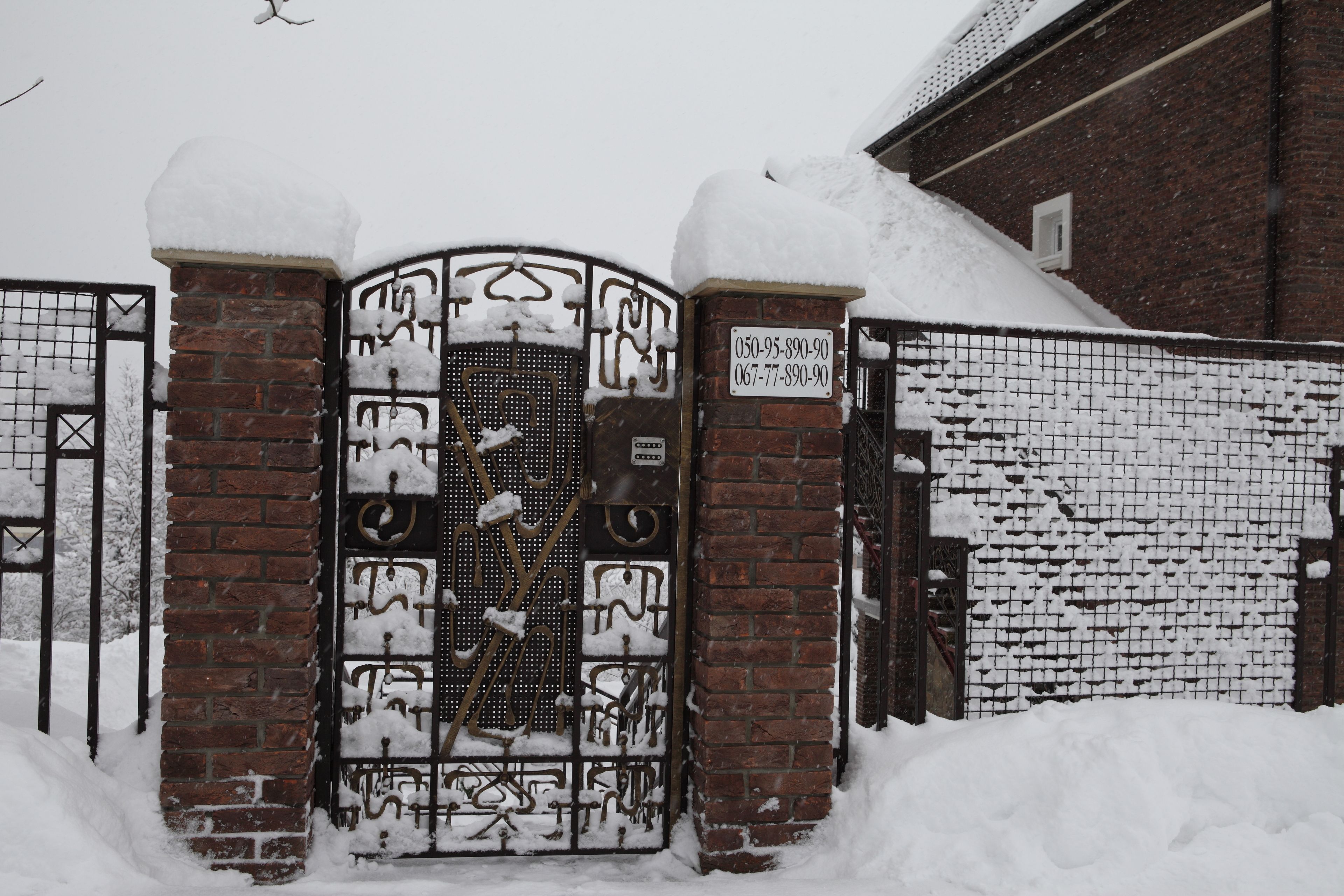 Una puerta cubierta de nieve con un muro de ladrillo y una reja metálica.
