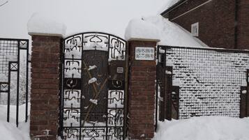 Una puerta cubierta de nieve con un muro de ladrillo y una reja metálica.