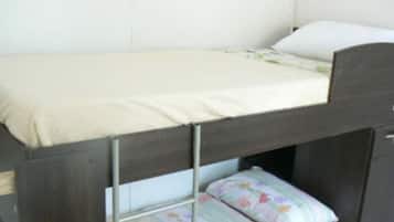 A bunk bed with a white headboard and a lower bunk with a floral-patterned pillow.