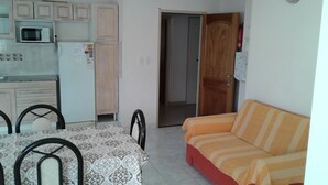 A compact living space with a kitchenette, a dining table with chairs, and a sofa.
