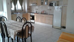 A compact kitchen with a dining table, chairs, a stove, microwave, and refrigerator.