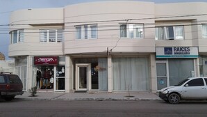 A building with a storefront labeled "Sonia UNISEX" and another labeled "RAICES INMOBILIARIA."