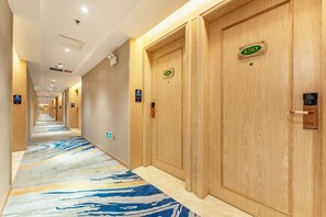 A hotel corridor with wooden doors, numbered room signs, and a patterned carpet. - Vienna Hotel (Shenzhen)