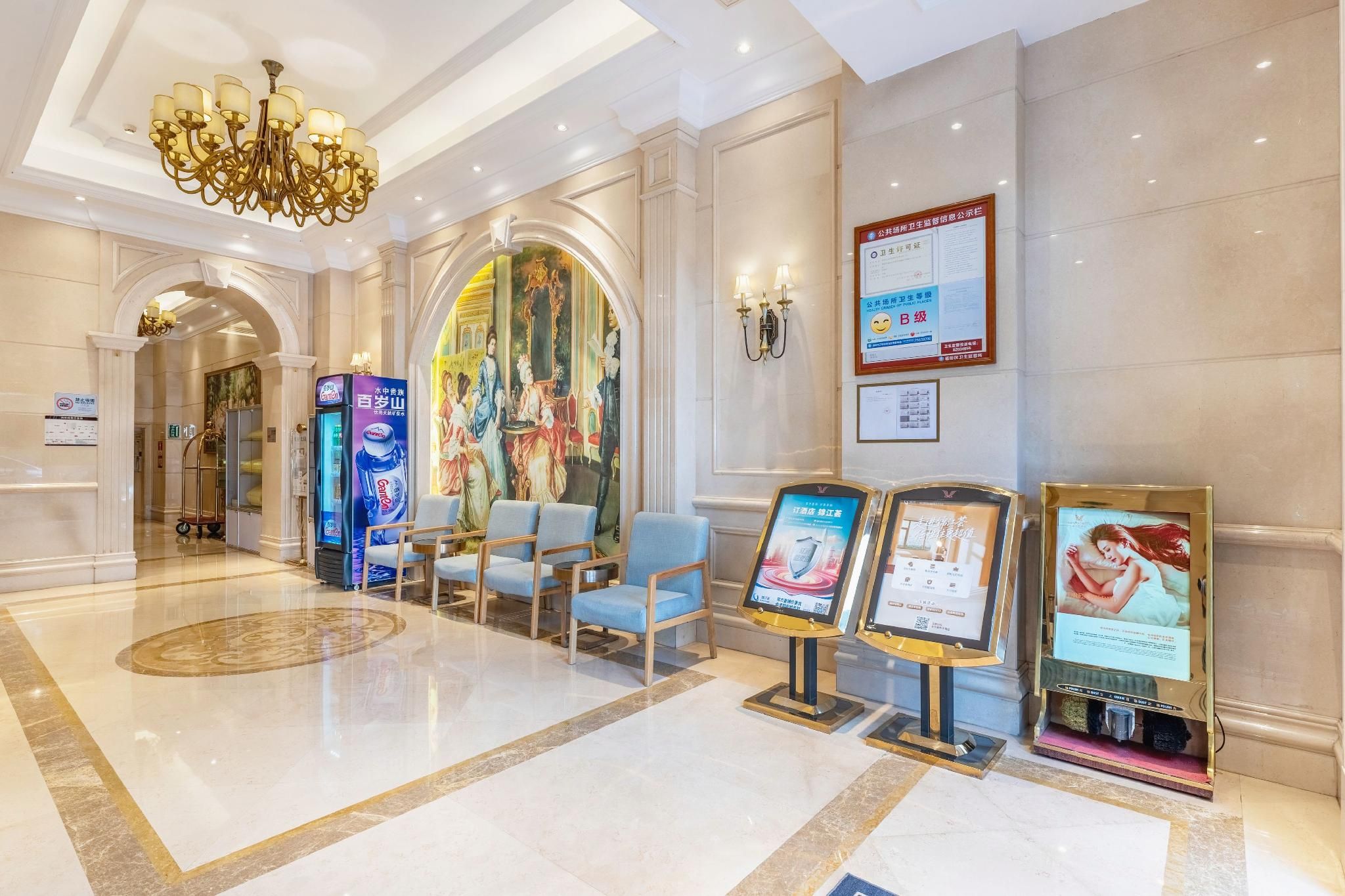 Eine Hotelhalle mit einer Kronleuchter, Sitzgelegenheiten und Informationsanzeigen.