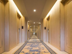 A hotel corridor with wooden walls, a patterned carpet, and overhead lighting. - Vienna Hotel (Shenzhen)