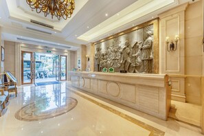 A spacious lobby with a marble floor, a grand chandelier, and a detailed wall sculpture. - Vienna Hotel (Shenzhen)