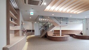 A modern interior with a central staircase, wooden accents, and a reception area. - View Lodge Biwa (Otsu)