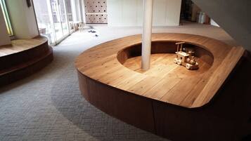 Una estructura circular de madera con un poste central, un pequeño camión de juguete de madera y un suelo con estampado de ladrillos.
