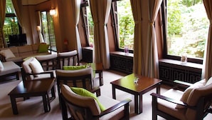 A cozy room with a sofa, armchairs, and a table, large windows with curtains, and a TV on a stand. - Yamanakako Garden Villa (Yamanakako)