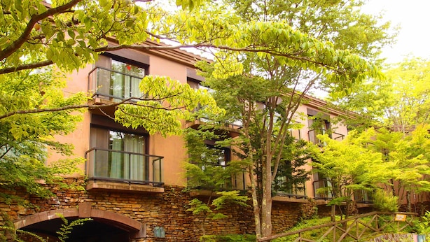 A multi-story building with stone walls, large windows, and a lush garden. - Yamanakako Garden Villa (Yamanakako)
