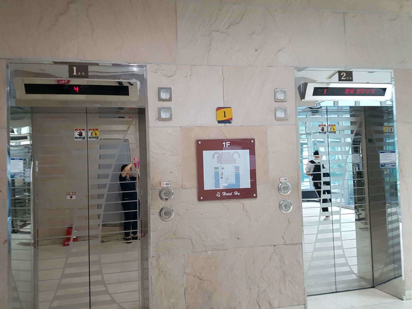 Two elevators with digital displays, a safety sign, and a hotel sign.