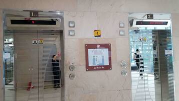 Two elevators with digital displays, a safety sign, and a hotel sign.