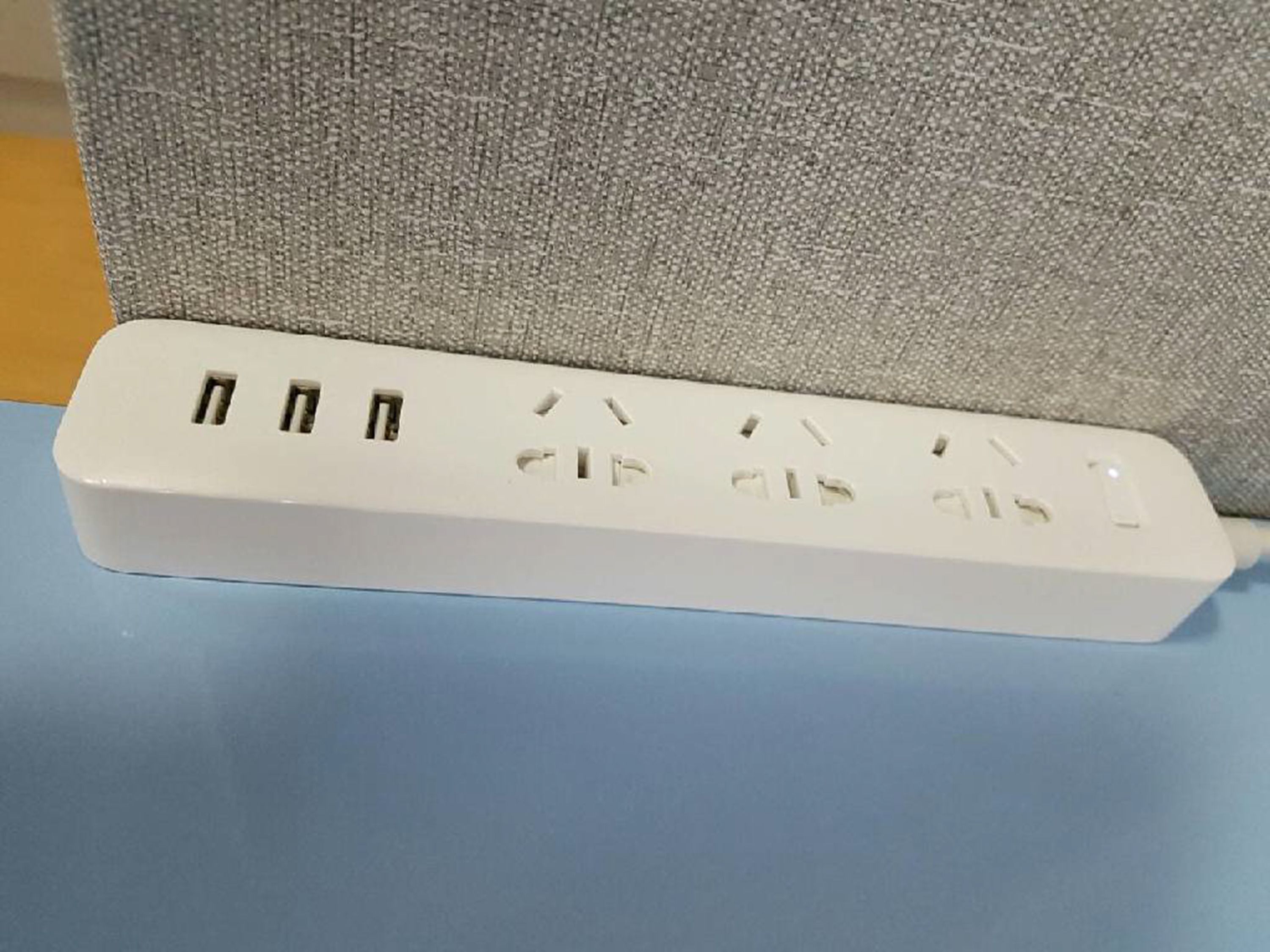 A white power strip with multiple outlets and USB ports on a blue surface.