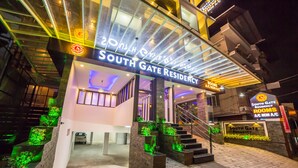 Das äußere Erscheinungsbild des South Gate Residency mit modernem Design, gekennzeichnet durch einen markanten Eingang, eine Glasfassade und beleuchtete Schilder.