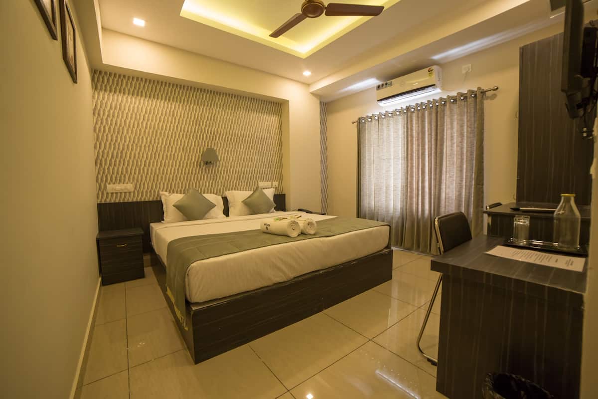 A modern hotel room with a large bed, a desk, and a ceiling fan.