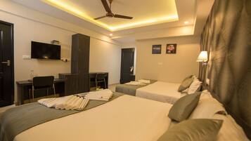 A hotel room with two beds, a desk, a TV, and a ceiling fan.