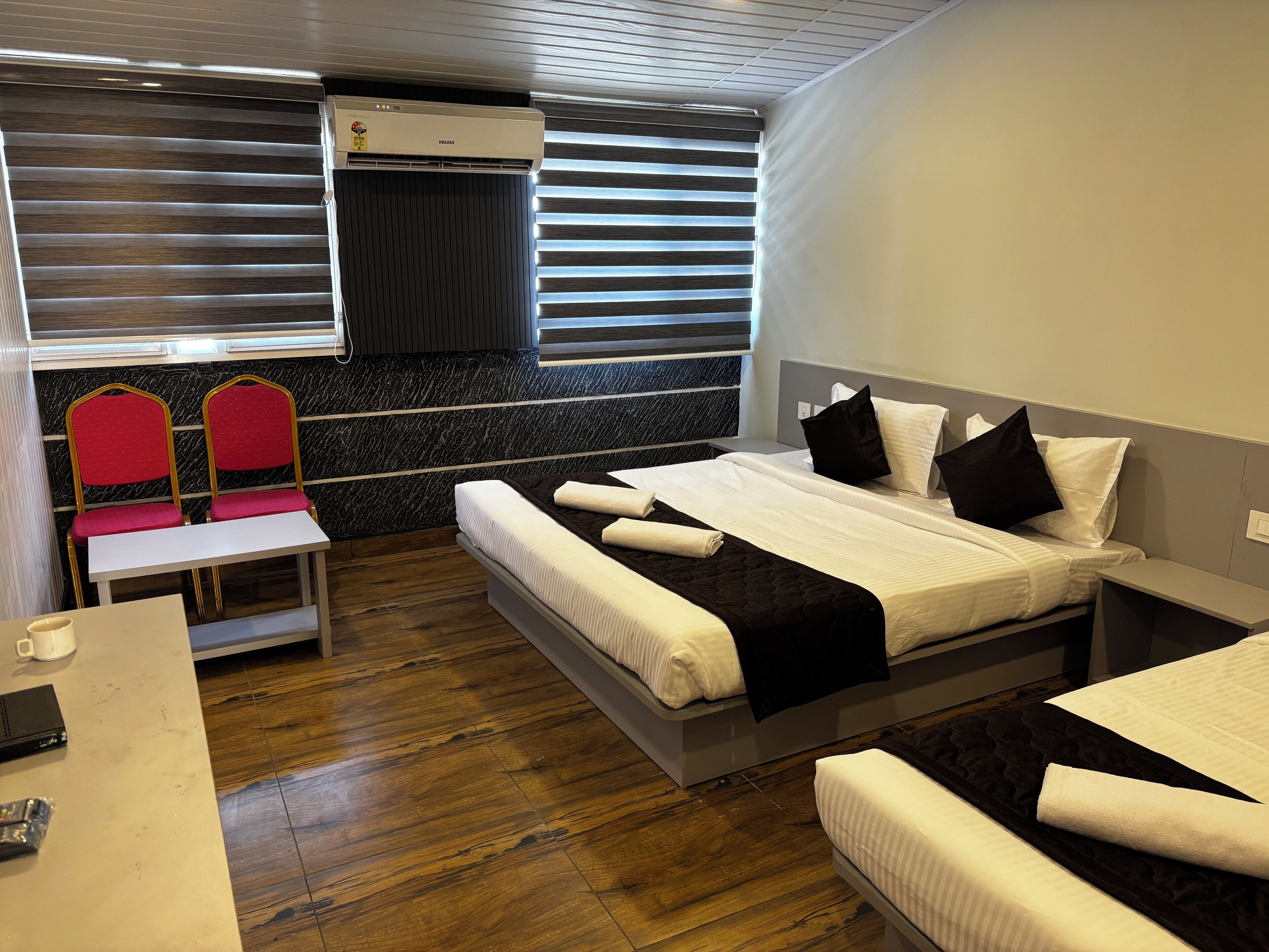 Una habitación de hotel con cama, mesitas de noche, un escritorio y una zona de estar con sillas.