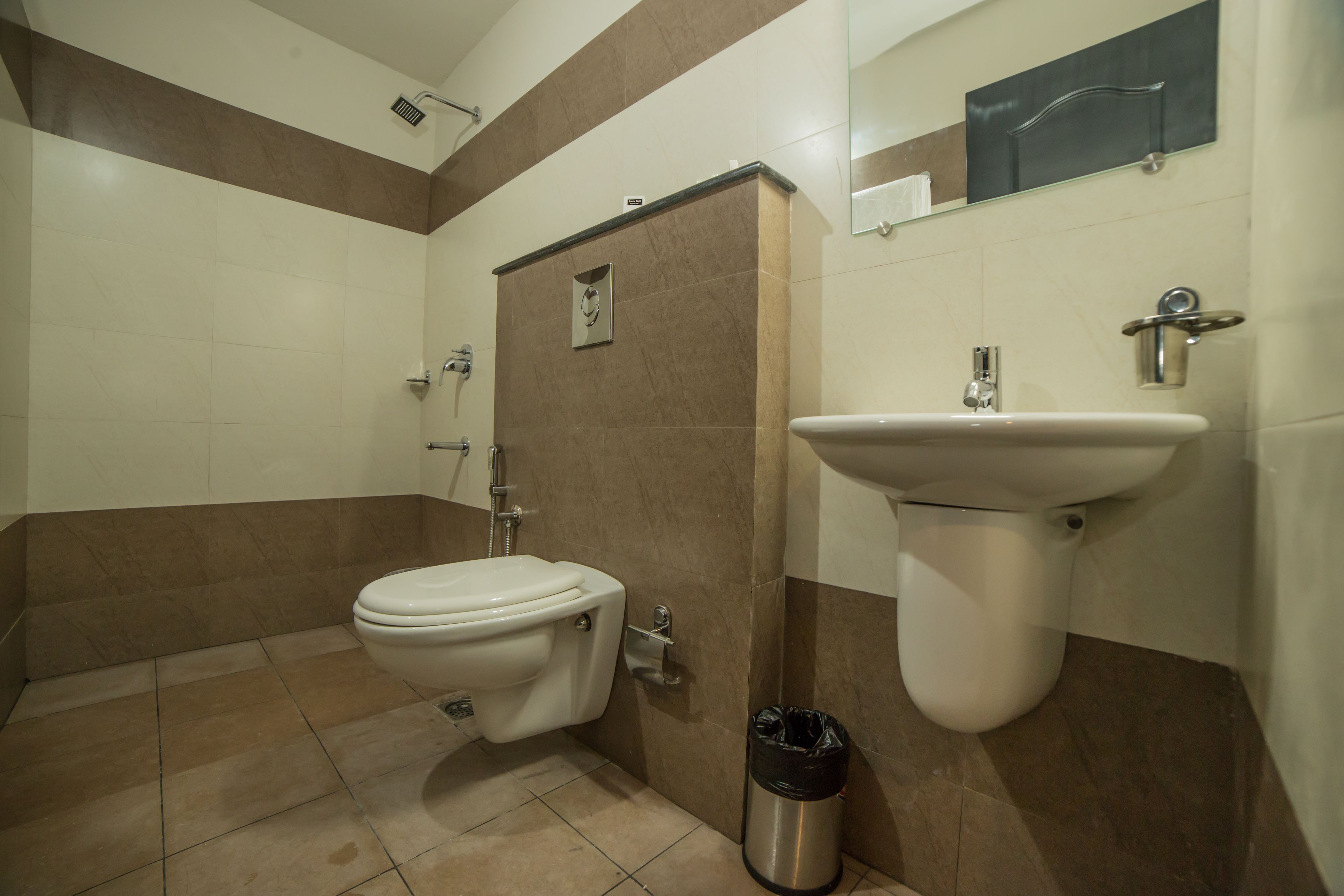 A bathroom with a toilet, sink, and trash bin.