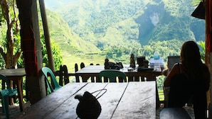 A table with a teapot, chairs, and a view of terraced fields and mountains. - Ramons Native Homestay and Restaurant (Banaue)