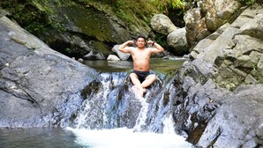 A person sitting on a rock by a waterfall in a natural setting.