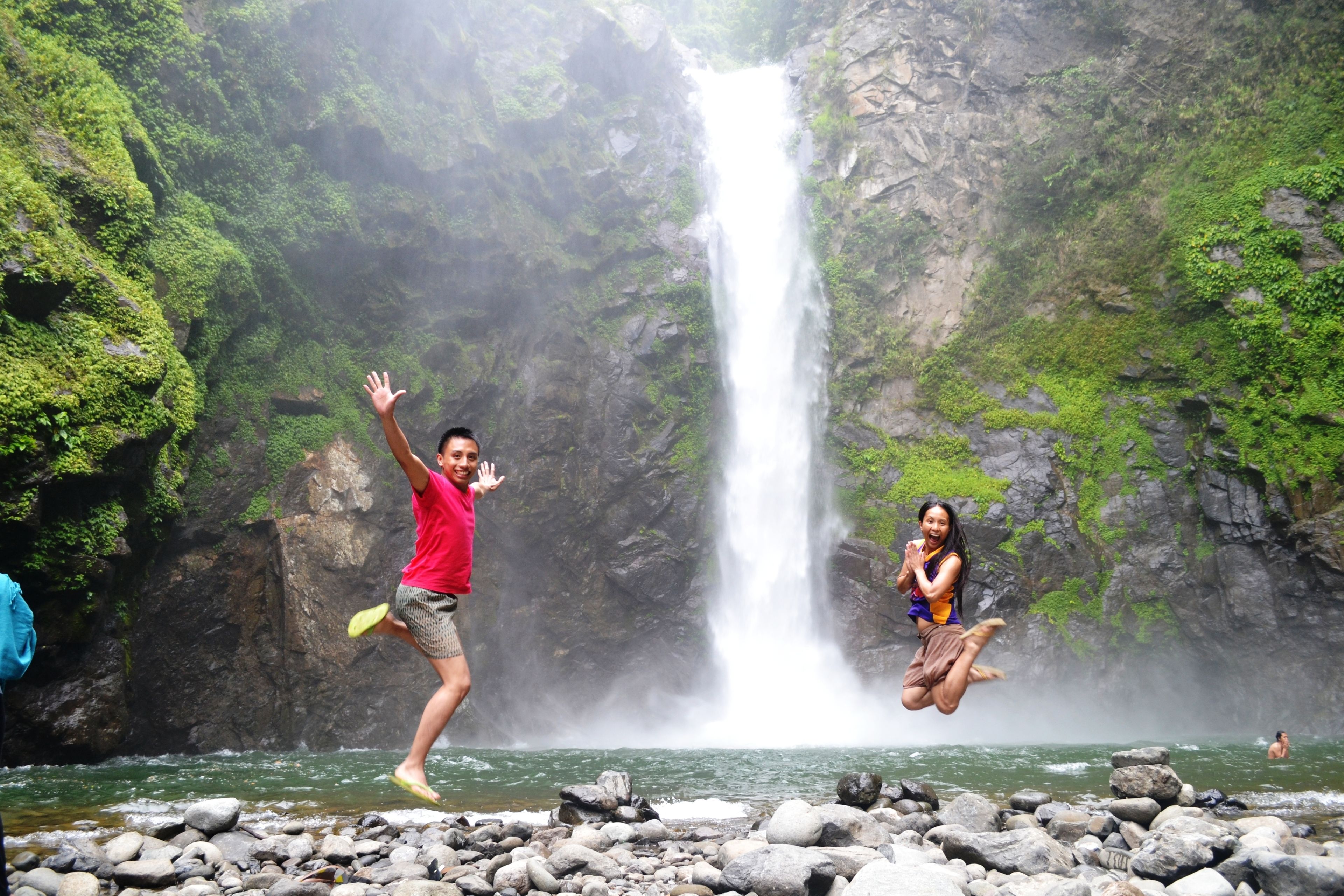 A waterfall with a rocky foreground and lush greenery.