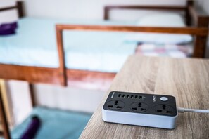 A power strip on a wooden table with a bed in the background.