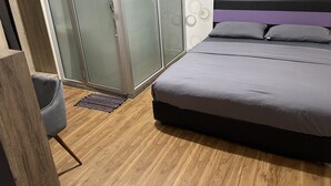 Un dormitorio con cama, una silla, armario y zona de ducha.