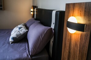 A bed with a headboard, a pillow, and a wall-mounted light fixture.