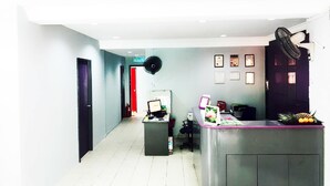 Zona de recepción con mostrador, computadora y diplomas enmarcados en la pared.
