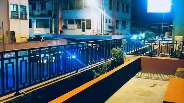 Vista nocturna de un edificio con balcón, barandillas y una fuente de luz brillante.