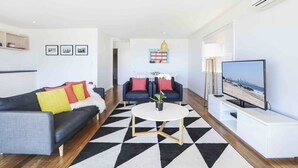 Ein modernes Wohnzimmer mit einer Couch, einem Couchtisch und einem Fernseher.