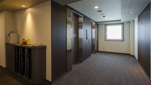 A hallway with a reception desk, a large window, and a carpeted floor. - Hotel Route-Inn Utsunomiya Yuinomori -Lightline Yuinomori Nishi- (Utsunomiya)