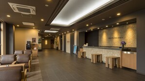 A hotel reception area with a reception desk, seating area, and a coffee machine. - Hotel Route-Inn Utsunomiya Yuinomori -Lightline Yuinomori Nishi- (Utsunomiya)