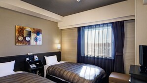 Ett hotellrum med två sängar, ett skrivbord, en stol, en tv och ett fönster med gardiner.