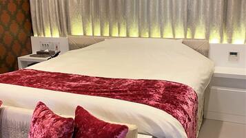 A modern bedroom with a large bed, a bedside table, and a nightstand.