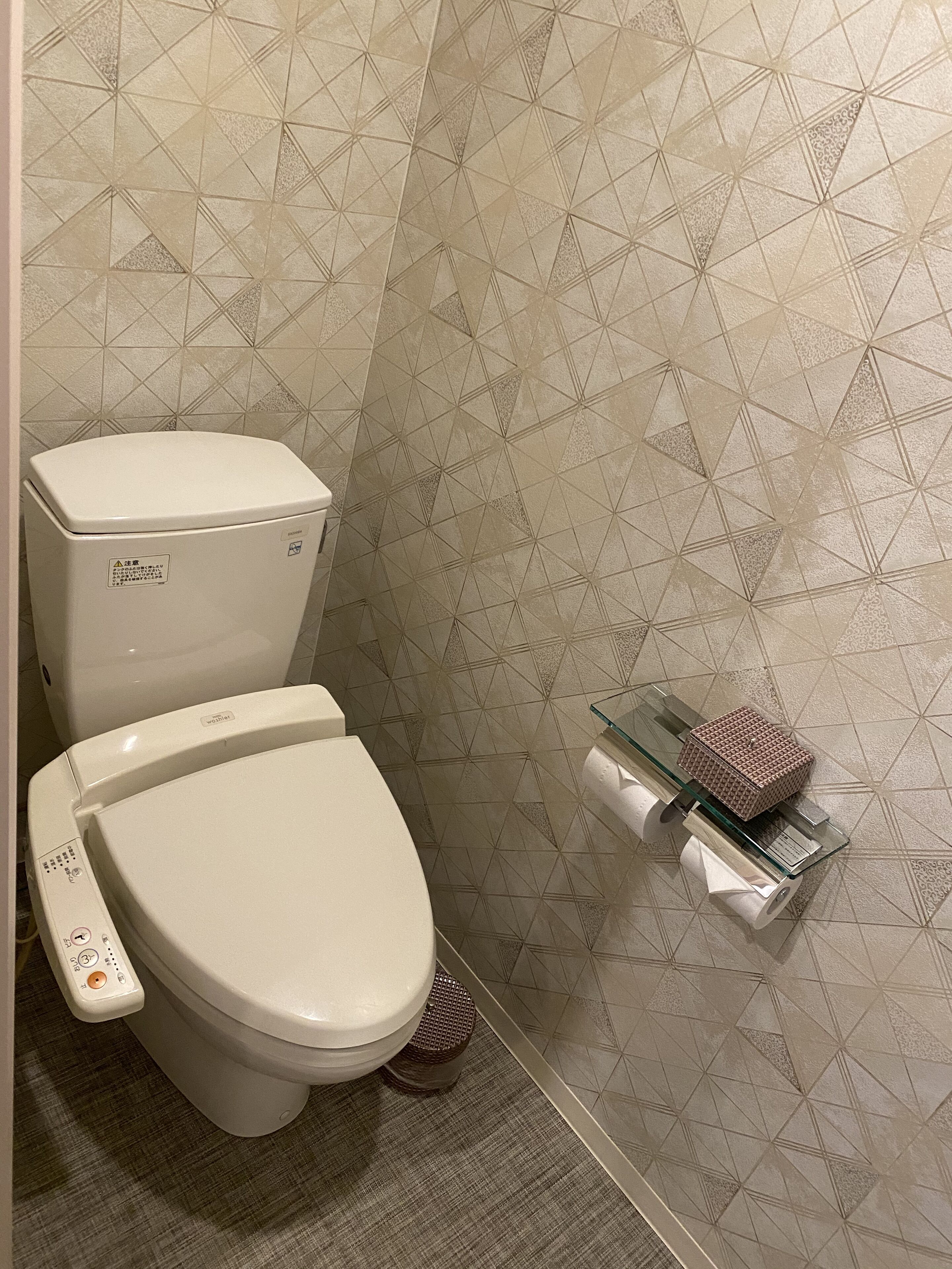Ein Badezimmer mit Toilette, Bidet und einer Wandseife in einer Glasflasche.