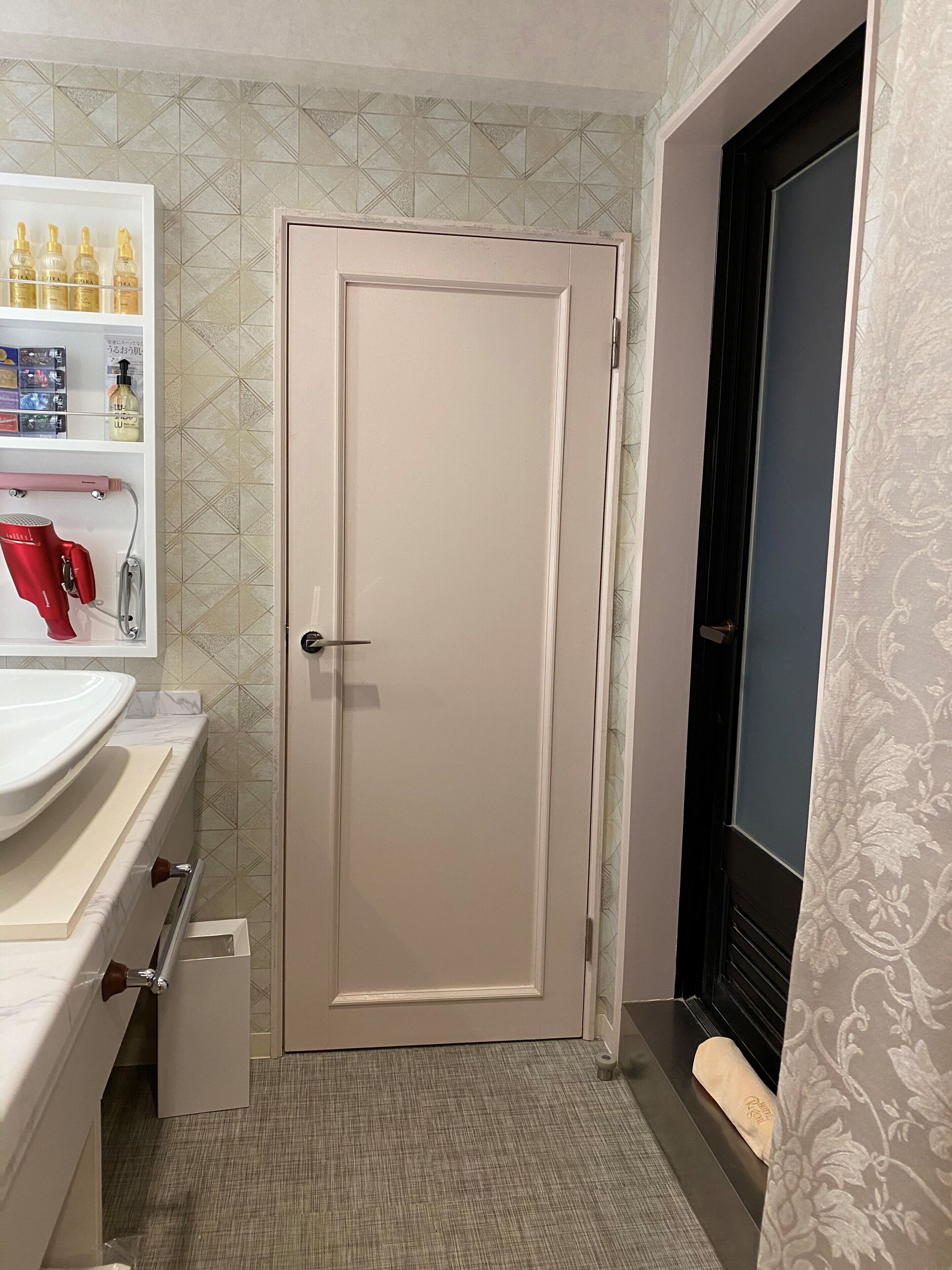 A bathroom with a white sink, a mirror, and a shelf with toiletries.