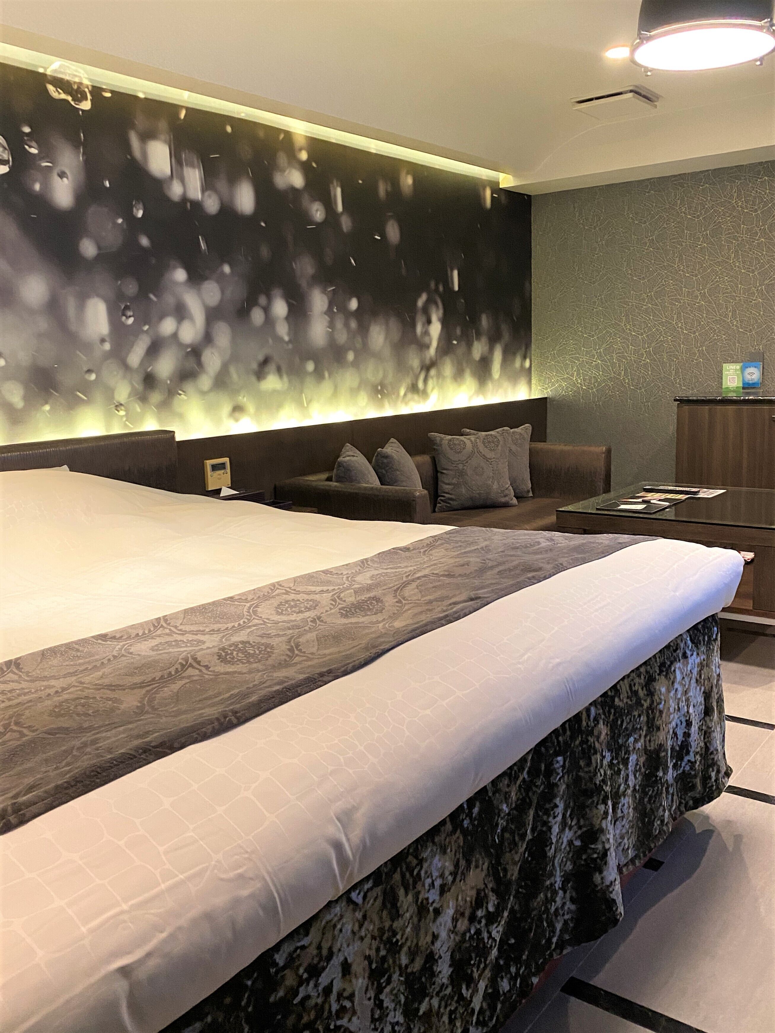 A modern bedroom with a large bed, a sofa, and a desk.