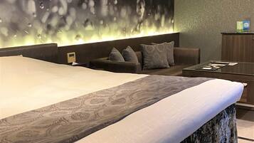 A modern bedroom with a large bed, a sofa, and a desk.