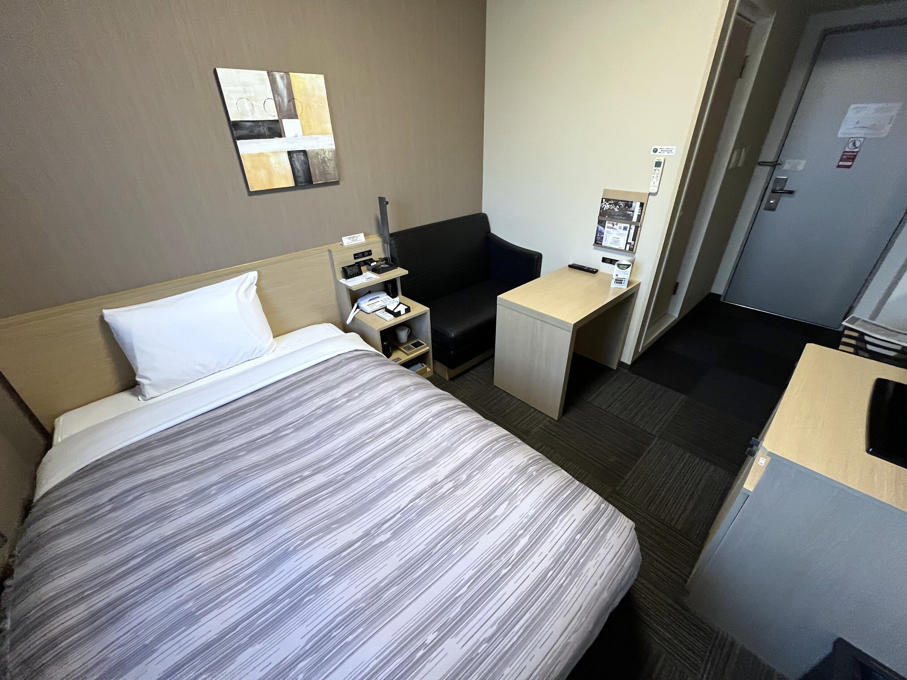 Una habitación de hotel con cama, escritorio, silla y una mesita.
