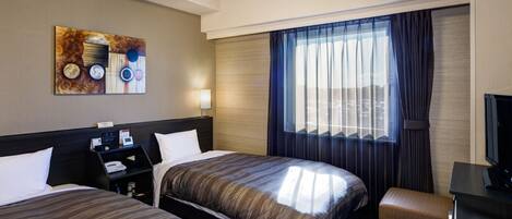 A hotel room with two beds, a desk, a chair, a television, and a window with curtains.