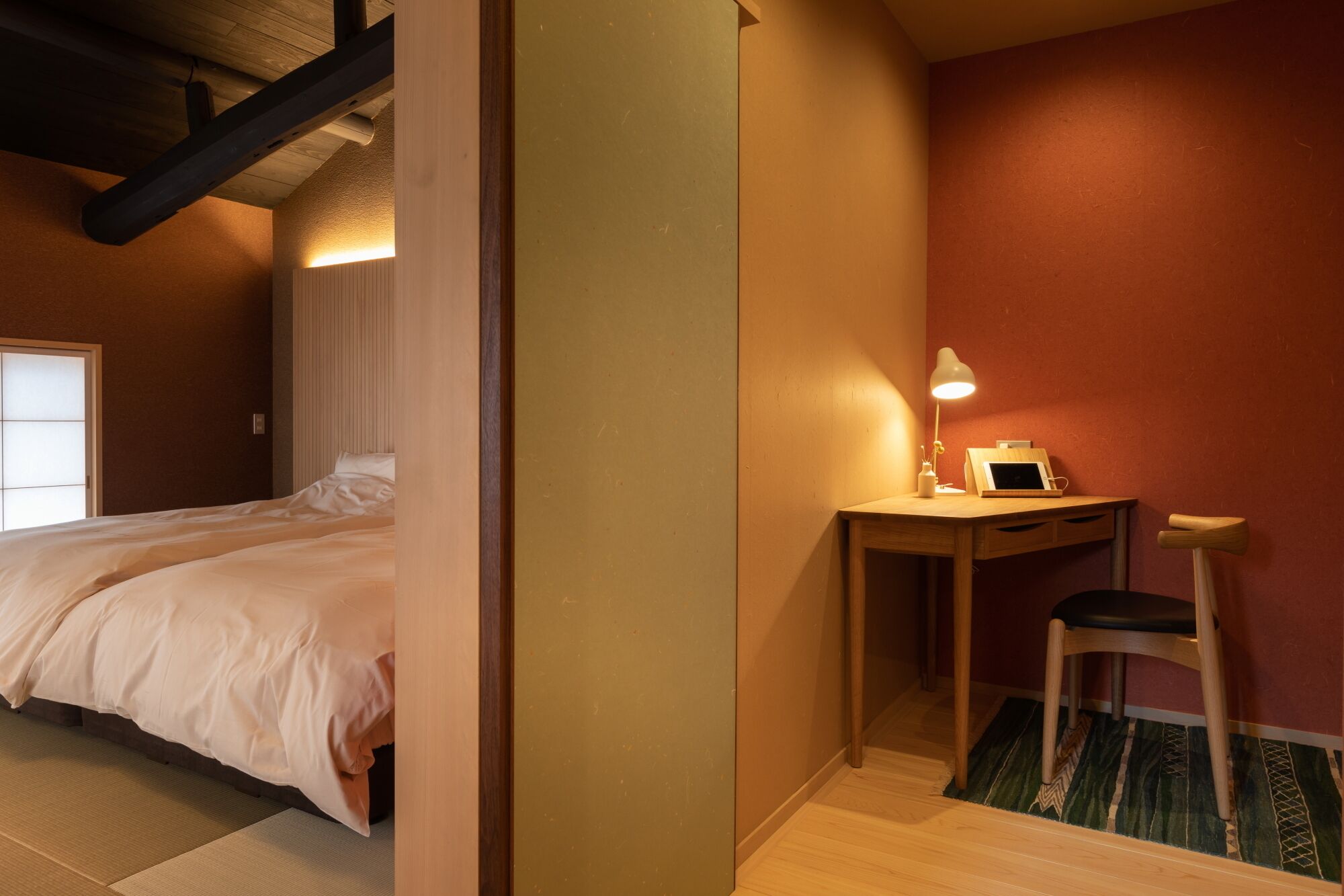 A bedroom with a bed, a desk with a chair, and a lamp.