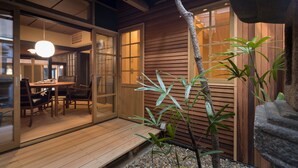 Una habitación tradicional japonesa con puertas correderas, una terraza de madera y plantas de interior.