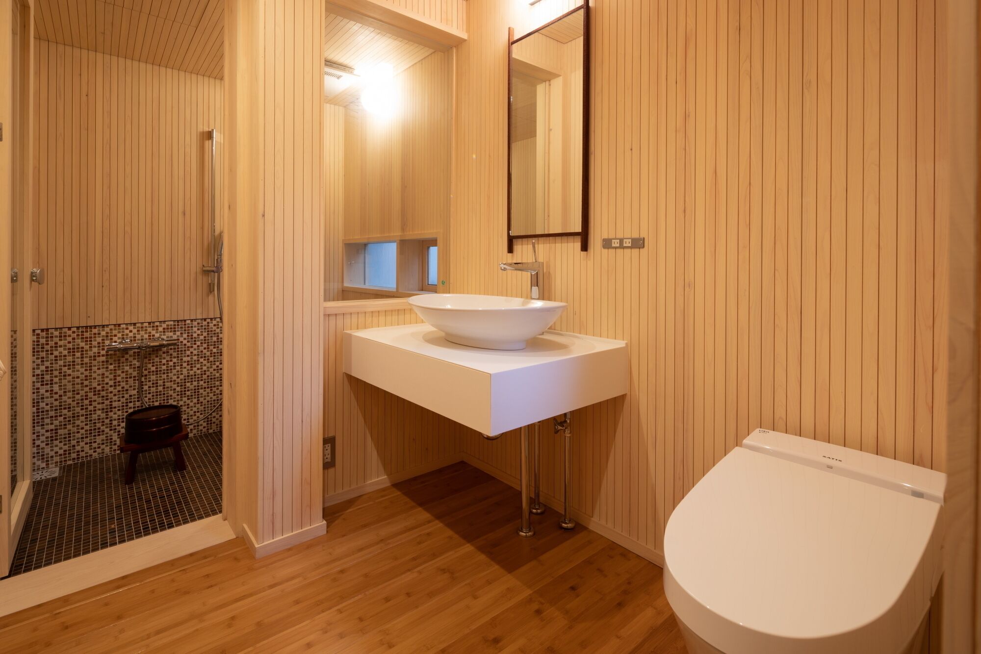 A bathroom with a wooden interior, a white sink, and a toilet.