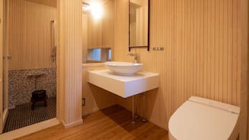A bathroom with a wooden interior, a white sink, and a toilet.