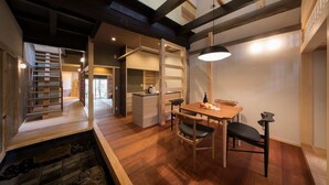 Un interior moderno con una mesa de comedor de madera, sillas y una lámpara colgante.