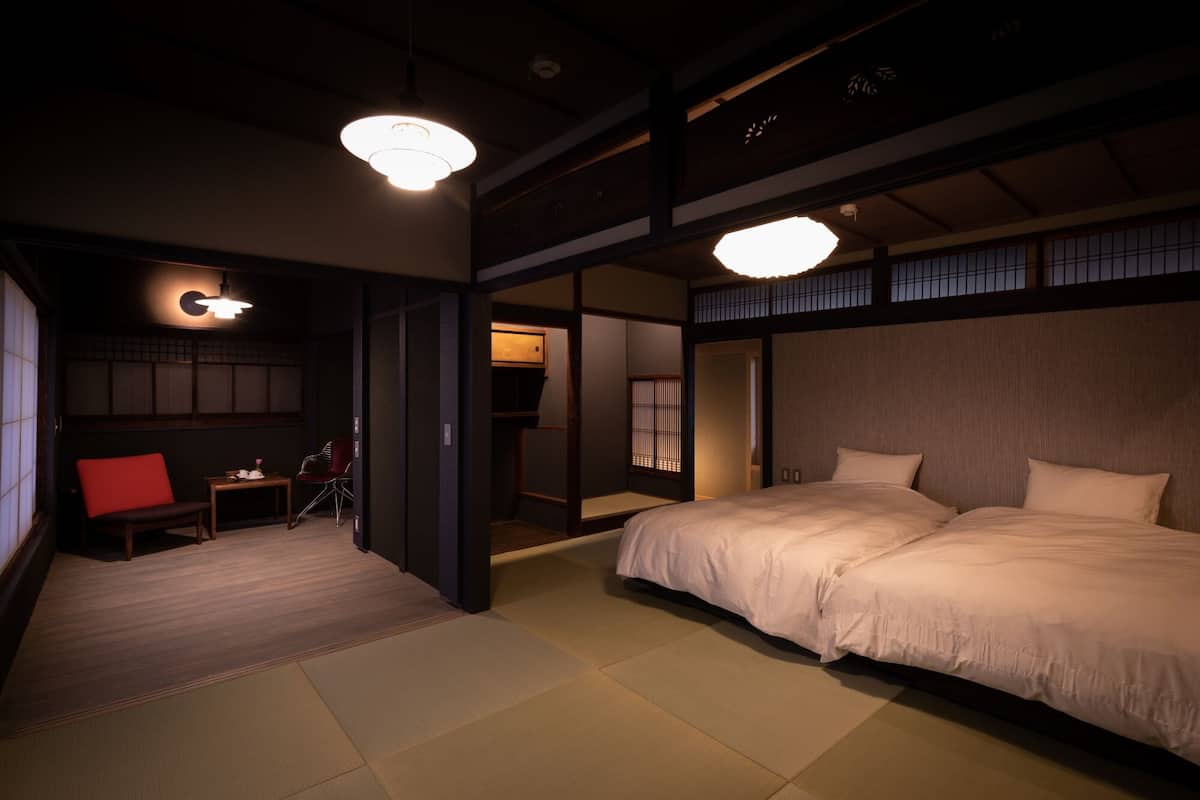 A traditional Japanese-style bedroom with tatami flooring, a low wooden bed, and sliding doors.