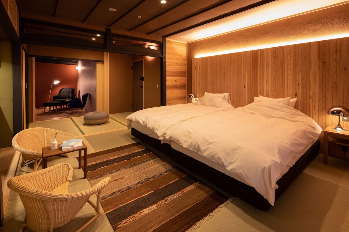 A modern bedroom with a large bed, a bedside table, a lamp, and a chair.